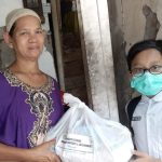 Ilham Zaidan Robbani salah satu pengurus LazismuKid’s menyerahkan paket sembako kepada Bundhe Pon, tetangganya (Basirun/PWMU.CO)
